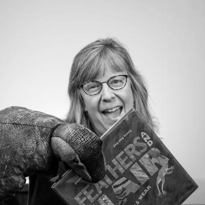 Photo of Kelly D with dinosaur puppet and book
