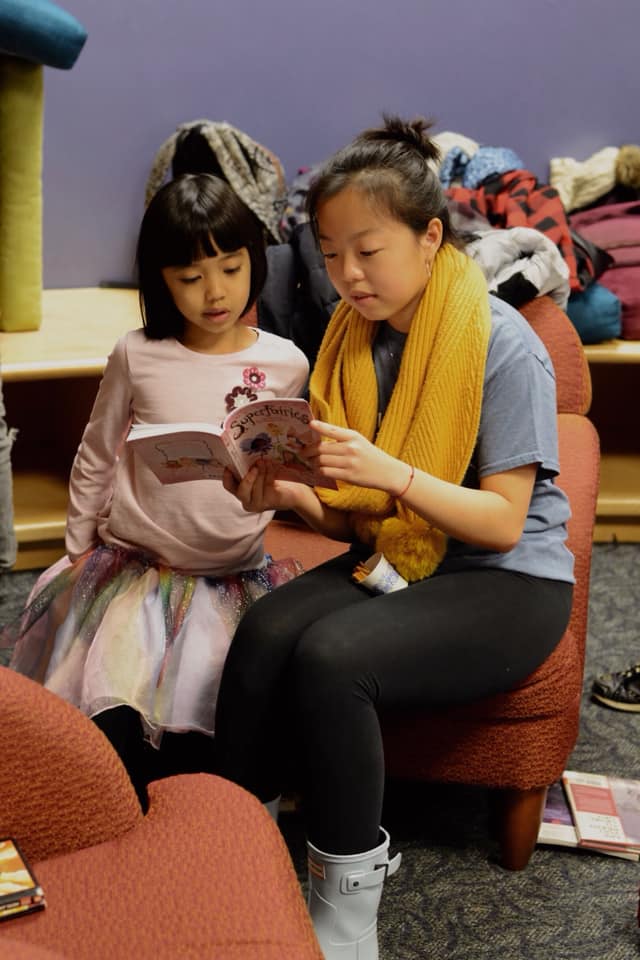 Young woman reading a book to a young child.