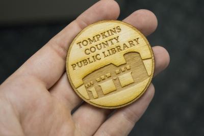 Image of open hand holding wooden token with TCPL logo