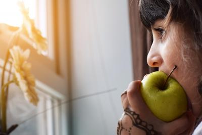 Little girl eating a green apple by a window