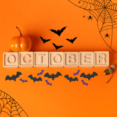 An orange background with children's building blocks that spell out "October". The image includes various "spooky" themes like bats, spiders and spiderwebs as well as a pumpkin and acorns