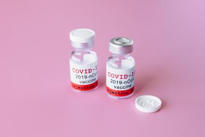 Image of covid-19 vaccine vials against a pink background