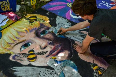 Image depicting a young man creating a chalk art drawing of a face