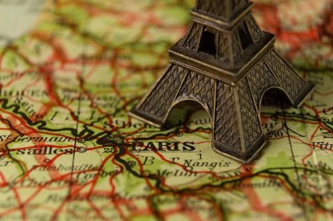 A picture of a map centered on Paris with a figurine of the Eiffel Tower
