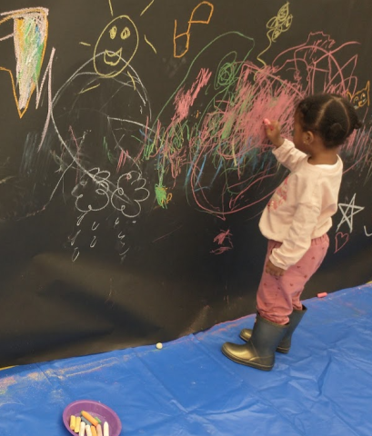 Toddler drawing with chalk on the wall