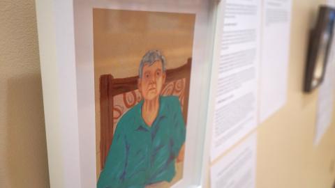 A portrait of a person in a green shirt, with a paper filled with unreadable text to the right of the portrait