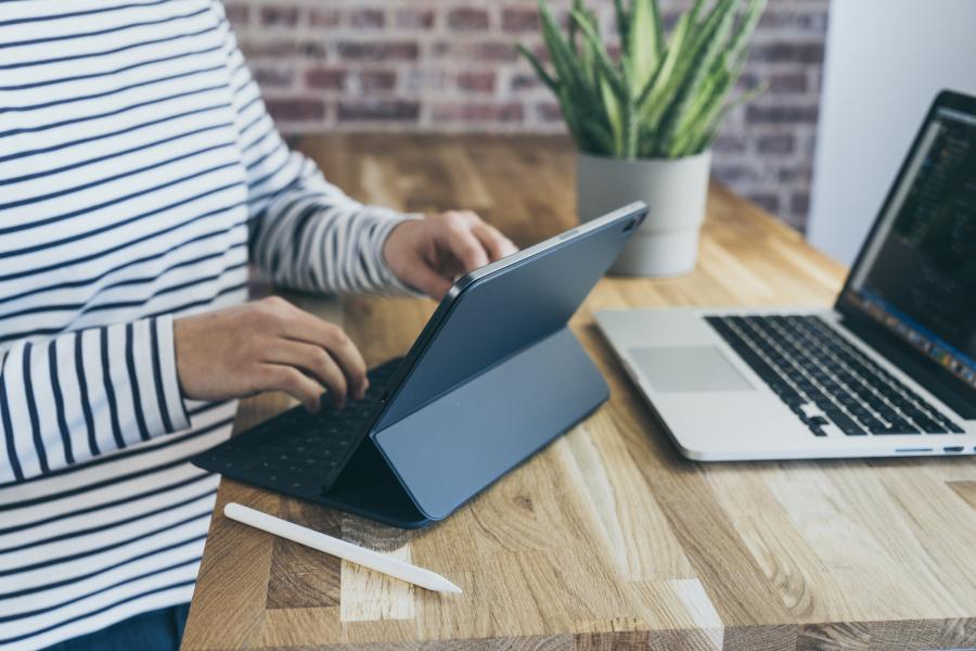 Image of person in striped shirt typing on ipad