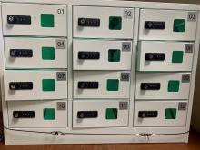 An image showing a 4 x 3 layout of locker doors (12 in total). Each has a combination lock and a window showing the contents (with a green light glowing visible through the windows)