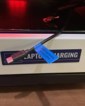 The laptop charging locker, opened to reveal a black cord with a usb-c adapter. It has a blue sticker on it that reads "PD45W Fast Charging for tablet/laptop"