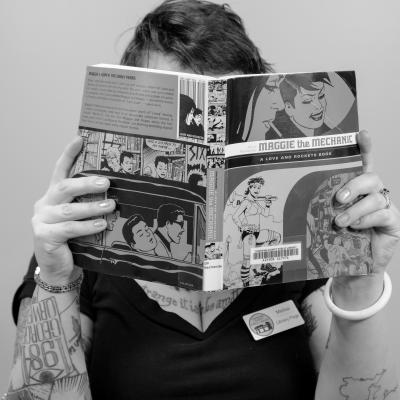 Photo of Melisa C. holding a book in front of her face