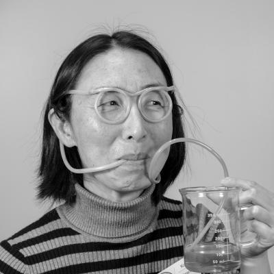 Photo of Kai Z wearing straw glasses and sipping water out of a beaker